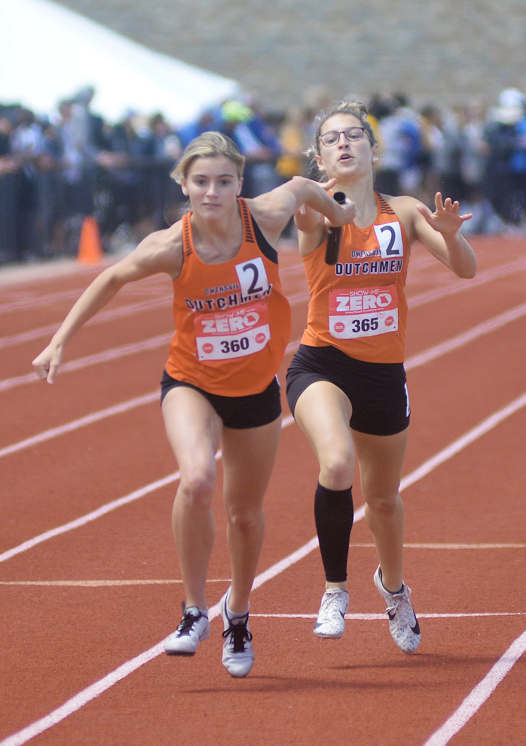 Emma Daniels (left) reaches back for the baton from Saylor Richardson during the Class 3 Girls 4x200-meter relay in which Owensville placed seventh in a new school record time of 1:49.11